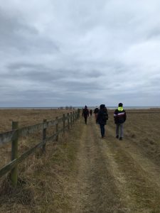 a cloudy sky and a dirt path with some hikers leading to the oresund sea in Sweden