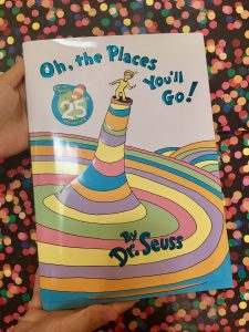 Oh, the Places you'll Go! by Dr. Seuss front cover with a child on top of colourful tree trunk