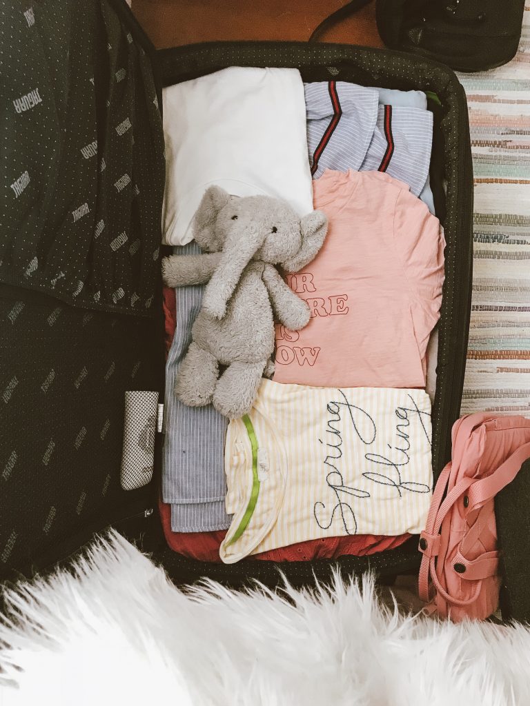Emi's suitcase, featuring a stuffed elephant, and t-shirts.