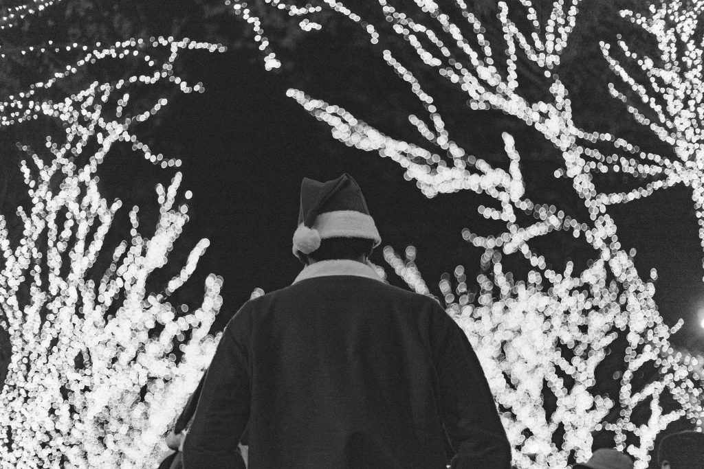 Man in a Santa costume with Christmas lights in the background.