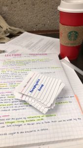 Cue cards on top of some notes. A Starbucks cup in the corner. 