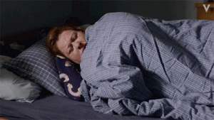 Gif of a grumpy woman pulling her covers over her head in the morning