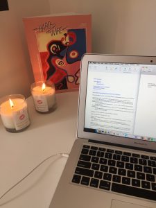 A computer sitting on a desk with candles. 