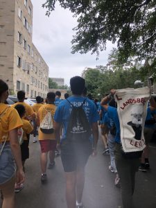 Orientation leaders and first year students walk side by side down the streets of Toronto carrying their houses' flags.