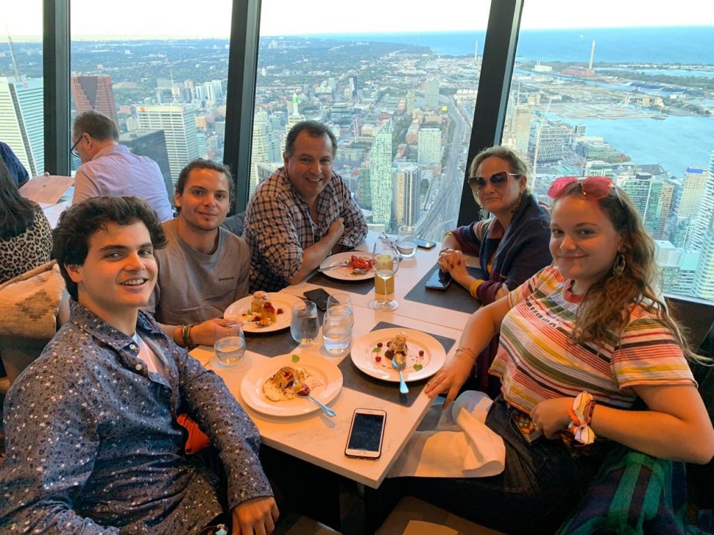 Francesca and her family having dinner on the CN Tower. They're all looking at the camera.