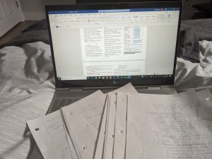 Laptop with text and sheets of paper in front