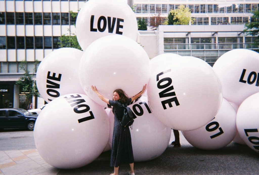 Olive hugging balloon balls that say "love".