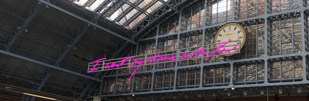 A pink neon sign that reads "I want my time with you" in St. Pancras Station, London.