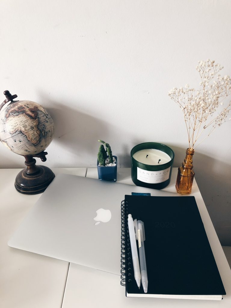 Picture of my laptop, a globe, candle, and agenda