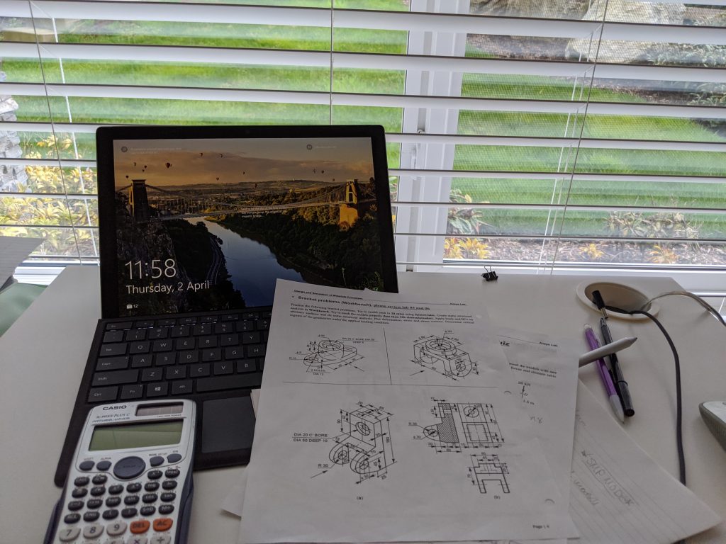 Open laptop with pages with diagrams and a calculator in front