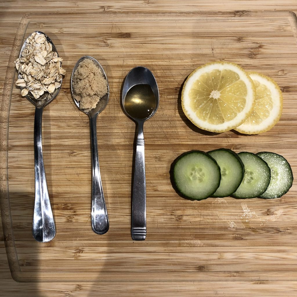 Spoons filled with honey, oats, sugar. Lemon slices and cucumber slices placed beside the spoons. 