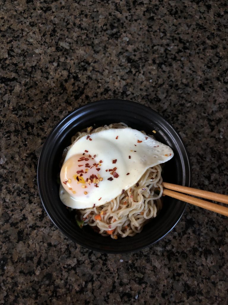 Bowl of raman with an egg seasoned with crushed pepper.