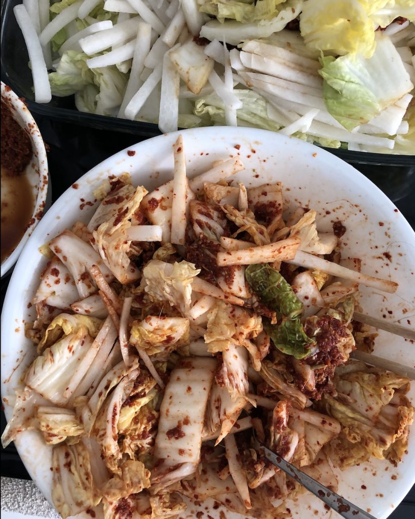 A picture of kimchi being mixed in a bowl.