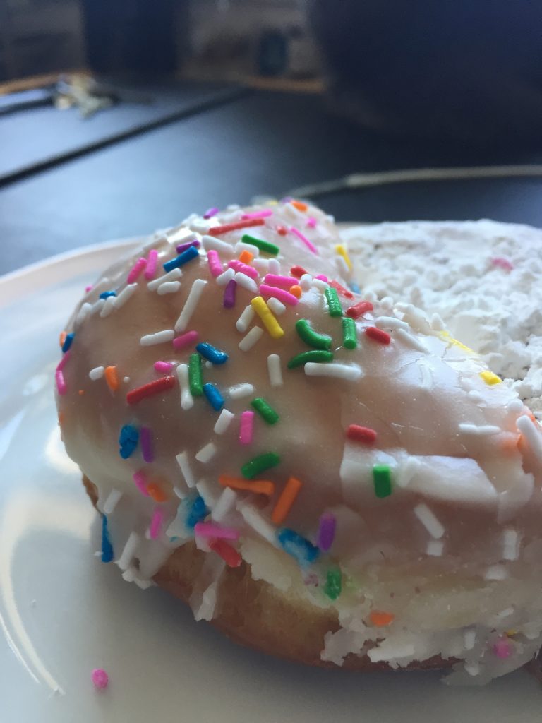 A close up picture of a sprinkles donut