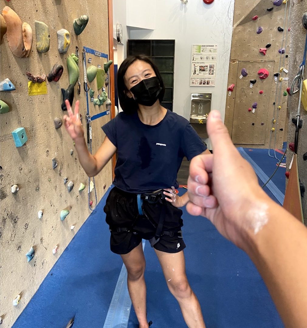 cheryl at a rock climbing gym, posing between two indoor rock climbing walls