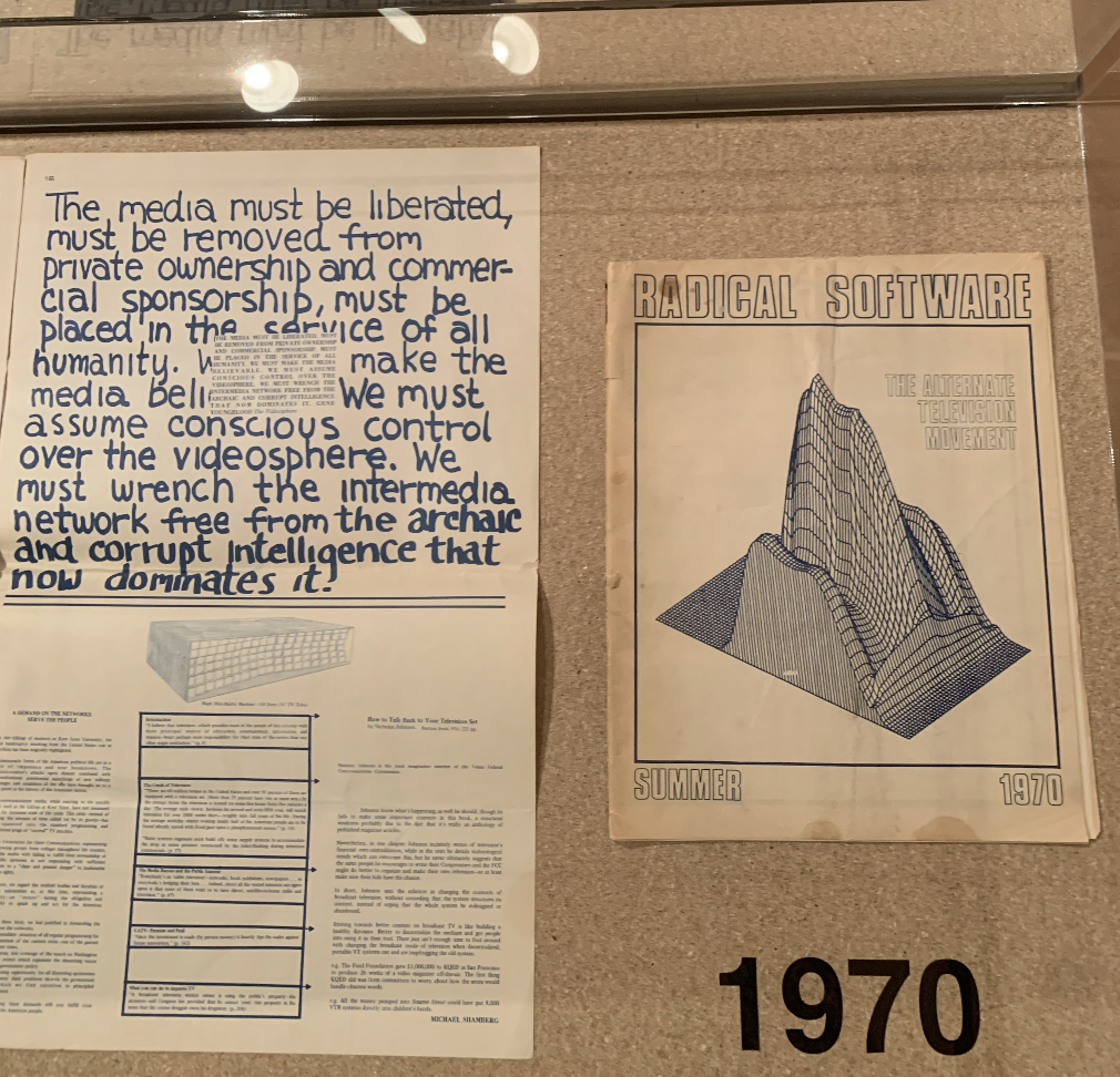a treatise and a cover of a 'radical software' booklet in a glass case titled 1970