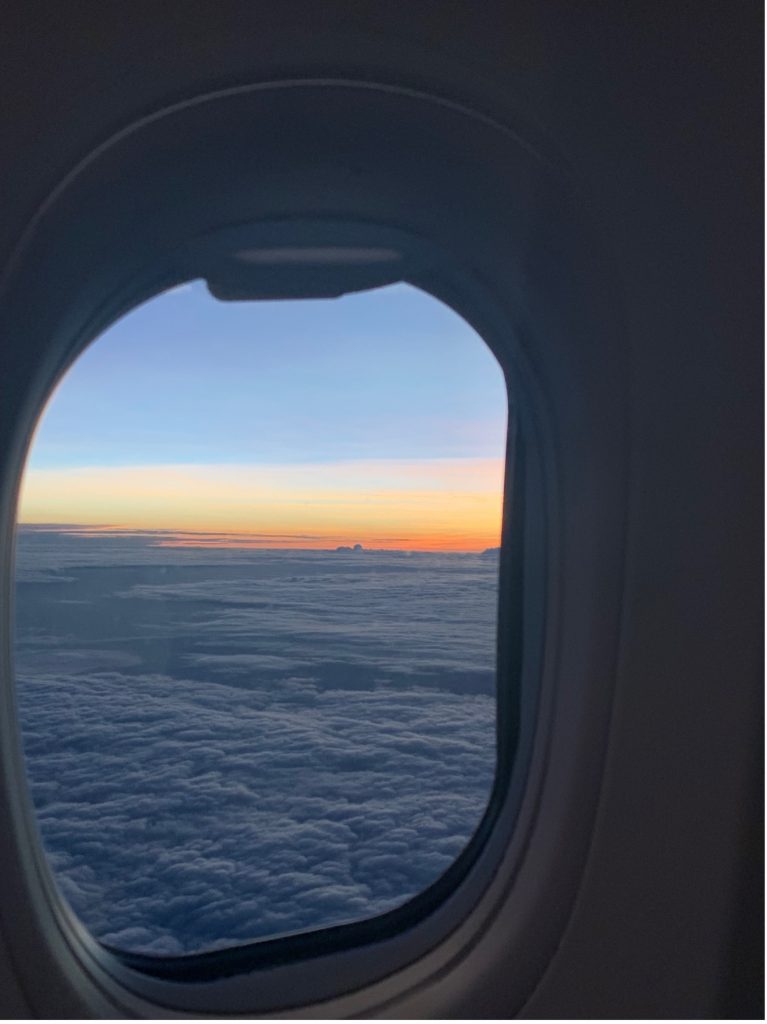 Looking out the window of an airplane to see the sunset 