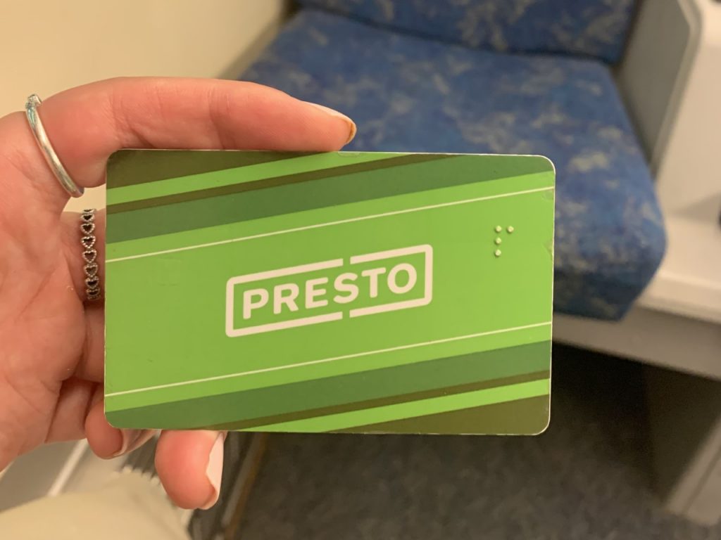 Green Presto card in hand with a blue seat in the background