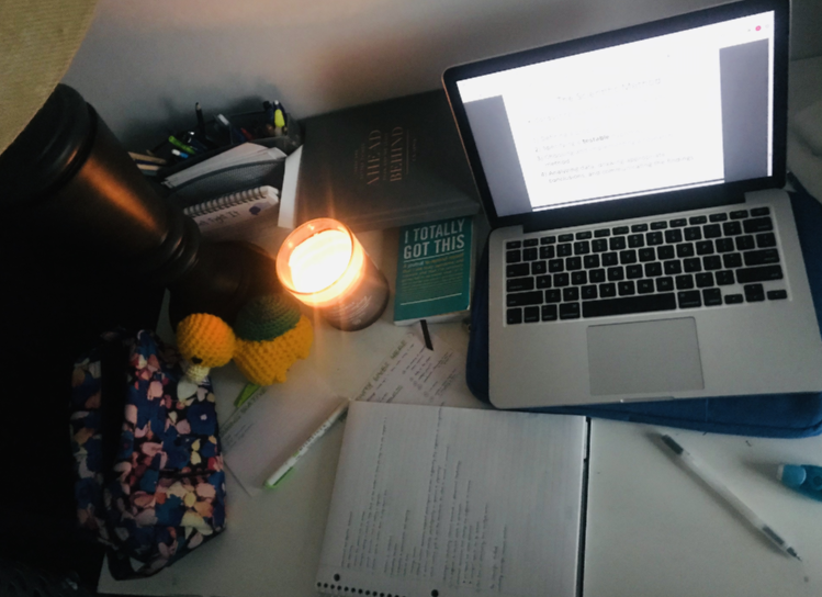 Workspace with a laptop, candle, notebook and pencils
