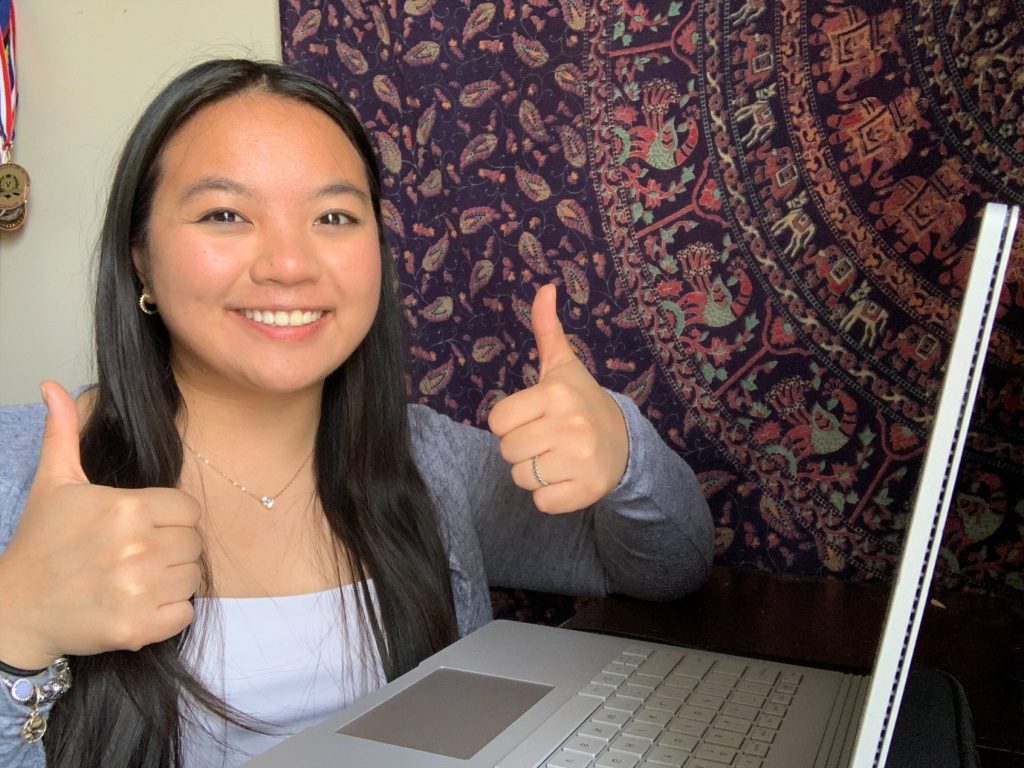 Jessica smiling with two thumbs up infront of her computer
