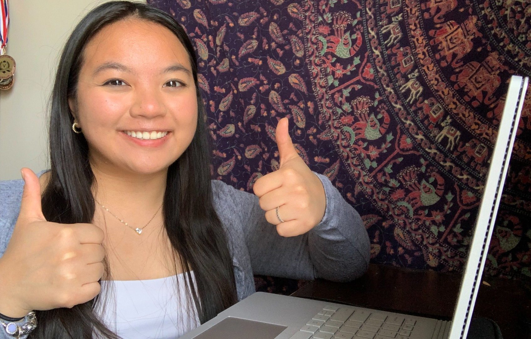 Jessica smiling with two thumbs up infront of her computer