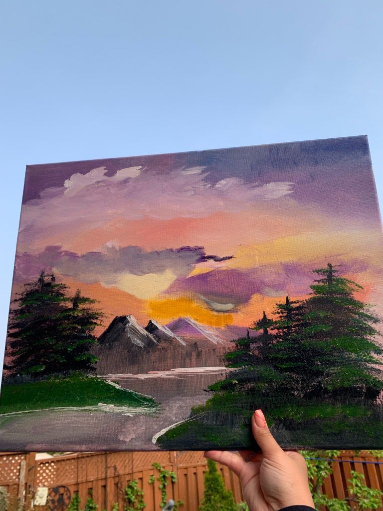 Painting of a sunset with mountains in the distance and green trees