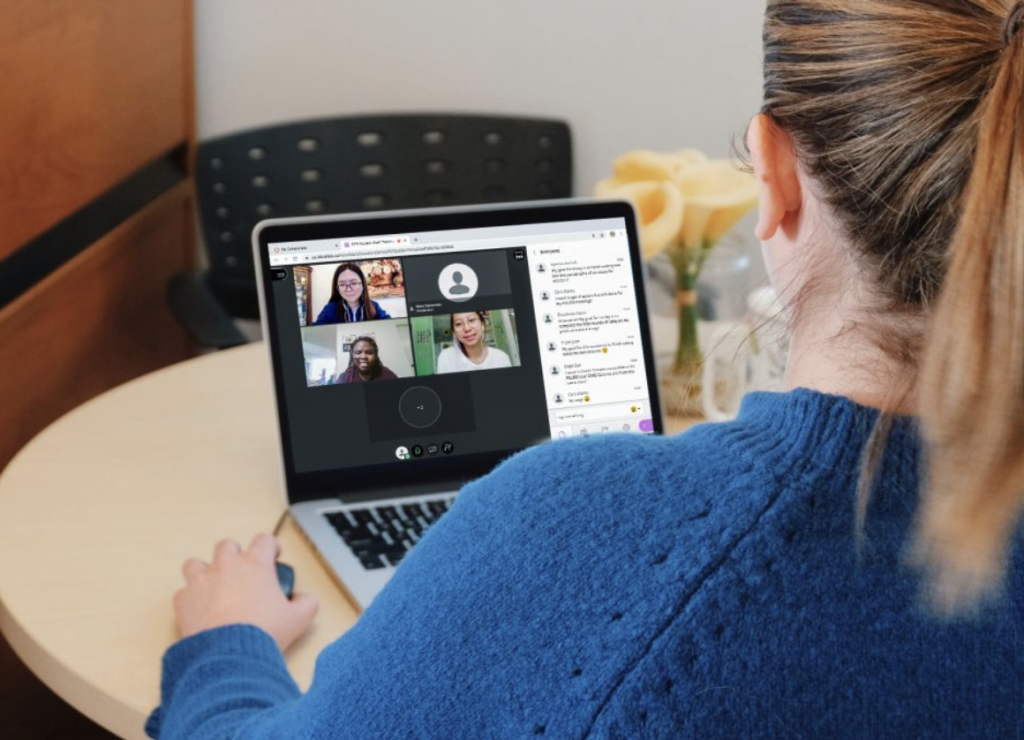 Photo of woman on a laptop in a video call with other people on the screen