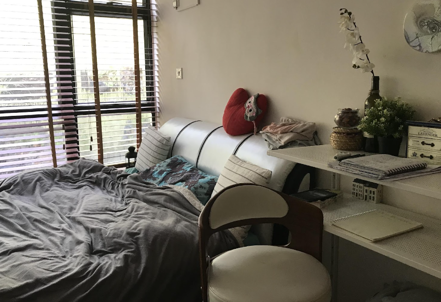 Photo of a bed beside a desk and window