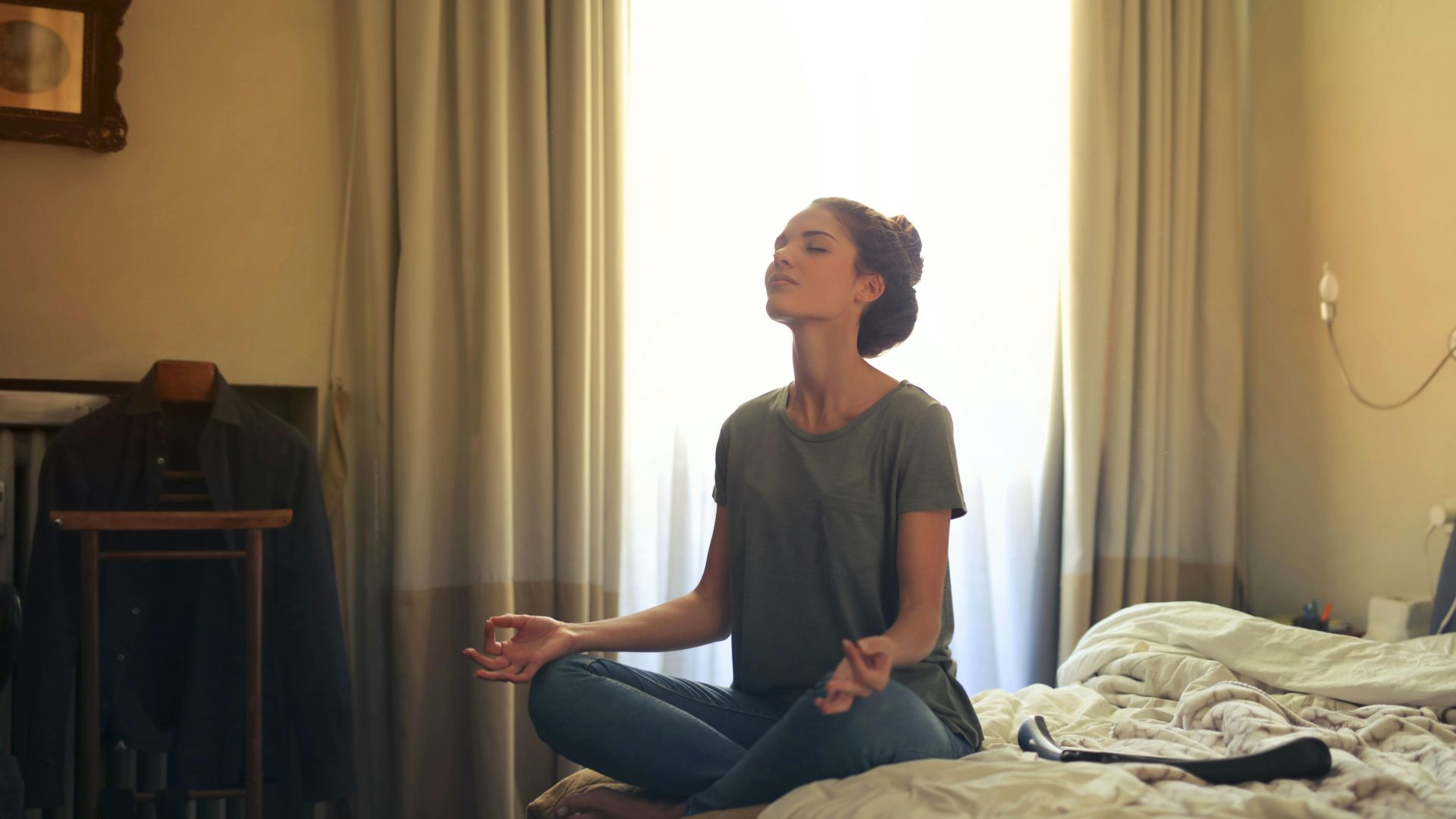 Photo of a person sitting on a bed and meditating