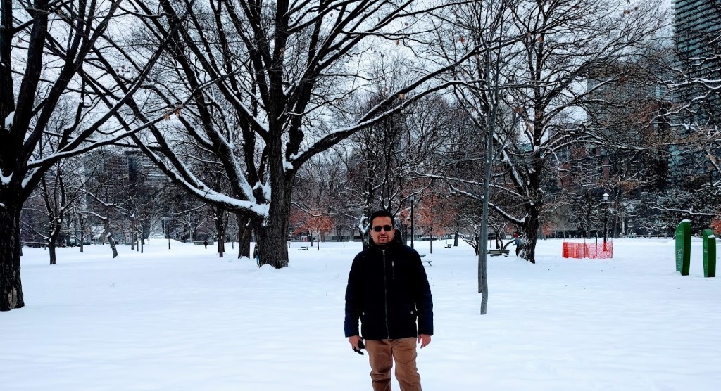 Shamim standing in a park filled with freshly fallen snow. 