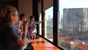 three team members look out the window at the iSchool and point out the fantastic view of campus.