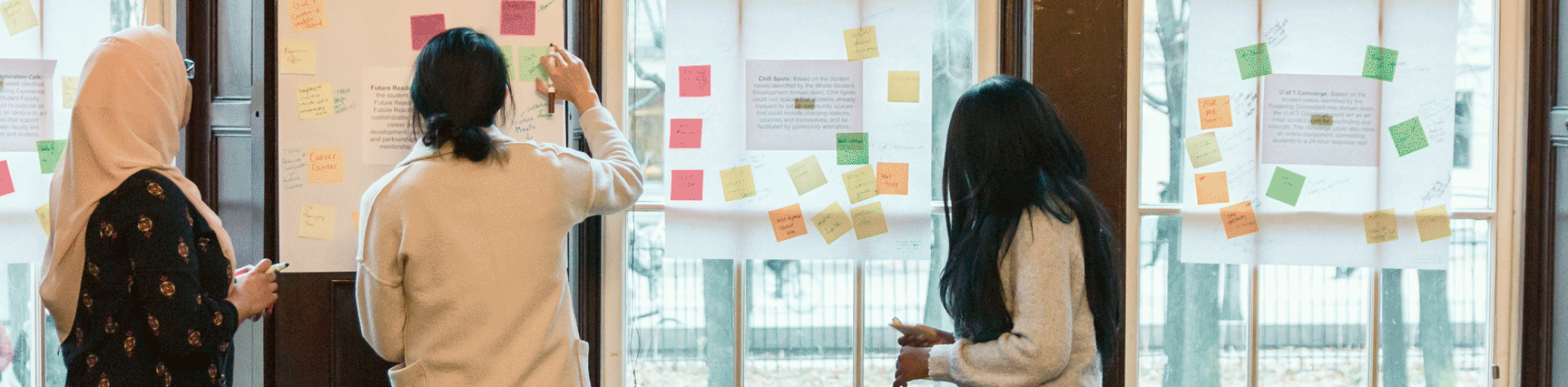 Three people looking at sticky notes and sketching.