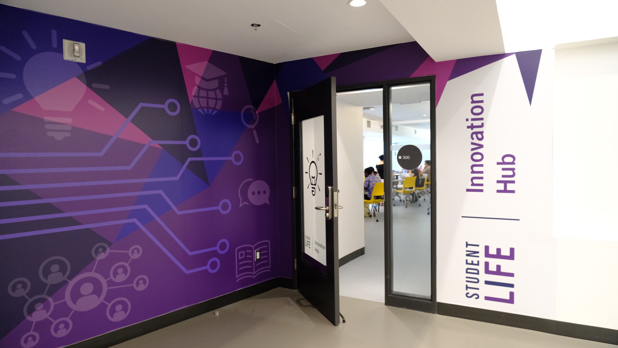 Outside of the Innovation Hub office. Purple wall mural with an open door.