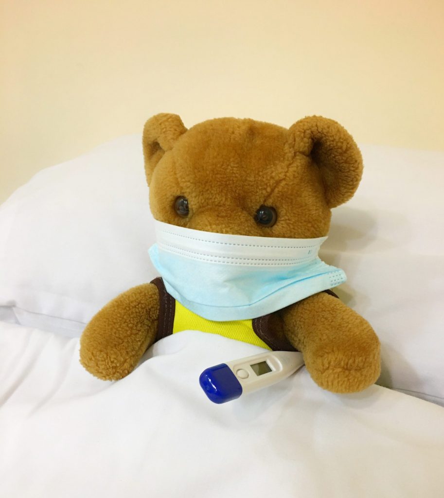 Stuffed teddy bear with mask and thermometer