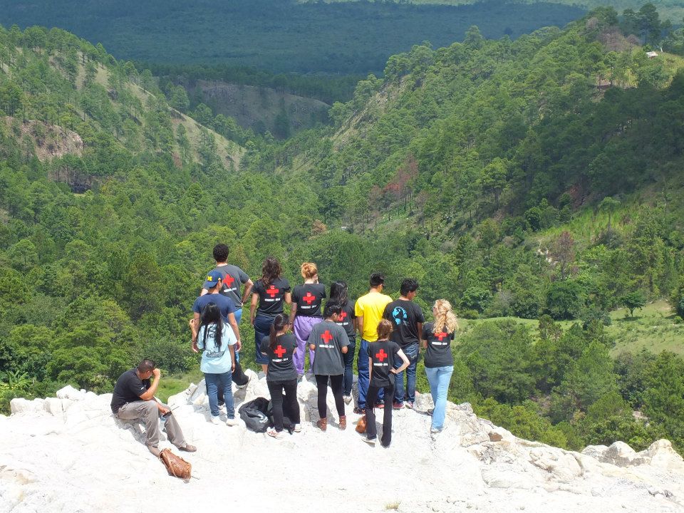 A group of our team members standing on the edge of a cliff overlooking the green scenery of the Honduran hillside.