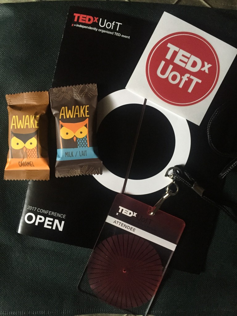 TEDxUofT badge, sticker, brochure, and some chocolates.