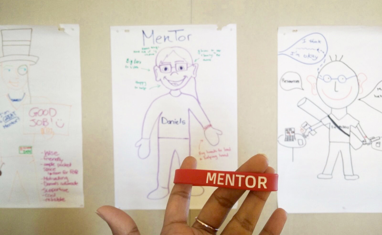 A picture of a red rubber bracelet with "Mentor" written on it.
