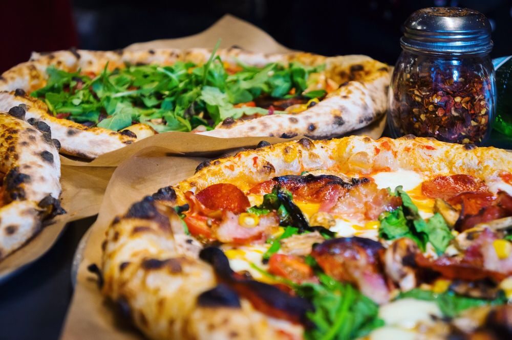 two pizzas, one with cheese and meat and one with arugula