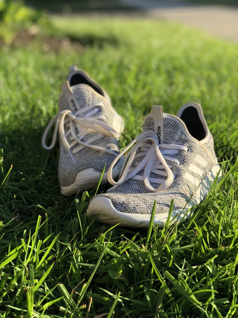 white and grey running shoes laying on grass.