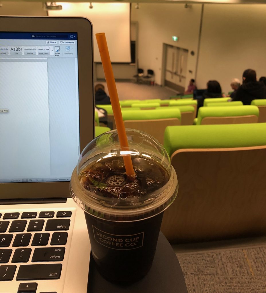 Picture of a cup of coffee, my laptop, and the inside of my lecture hall