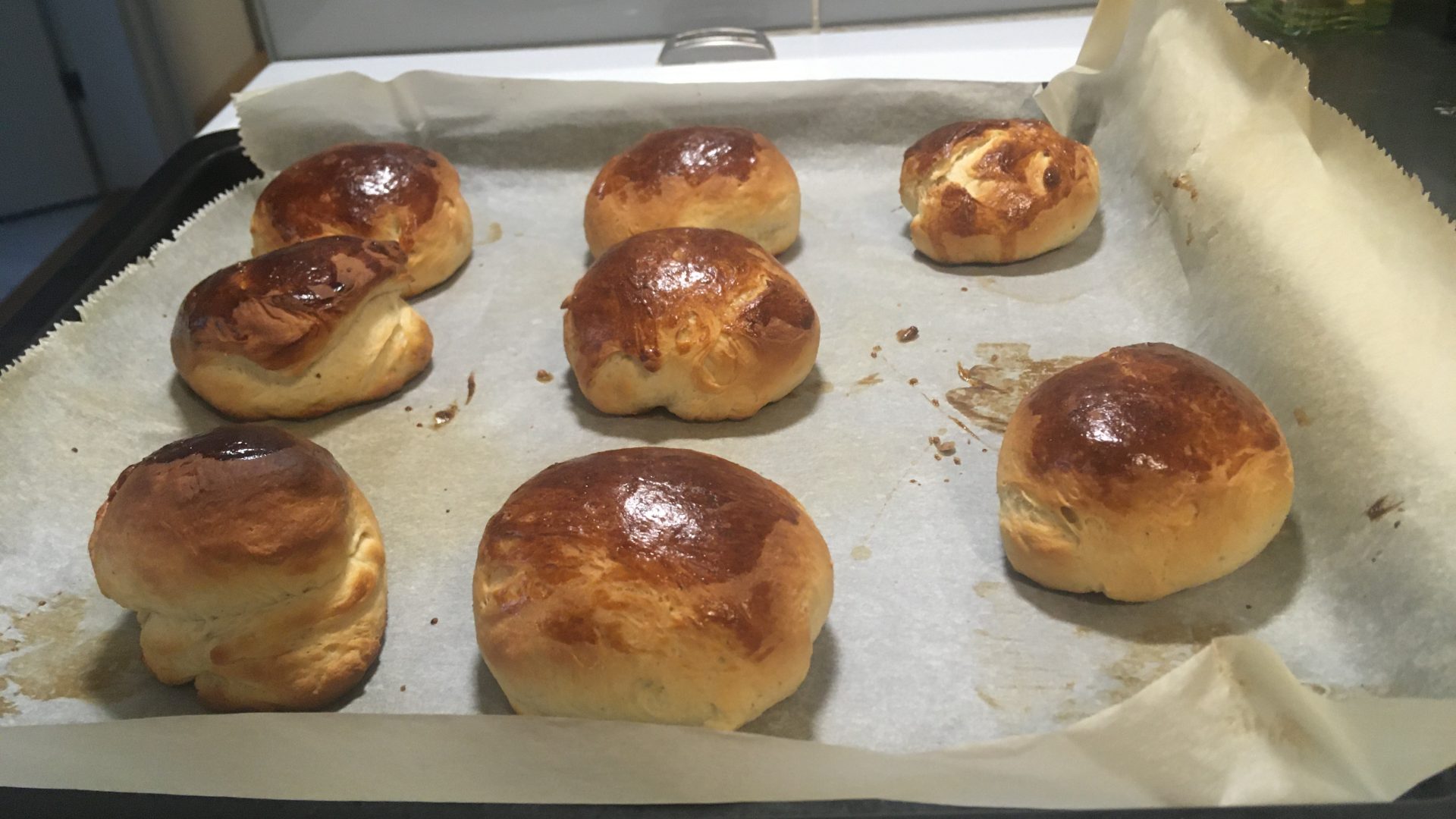 Fresh buns sit on a baking tray.