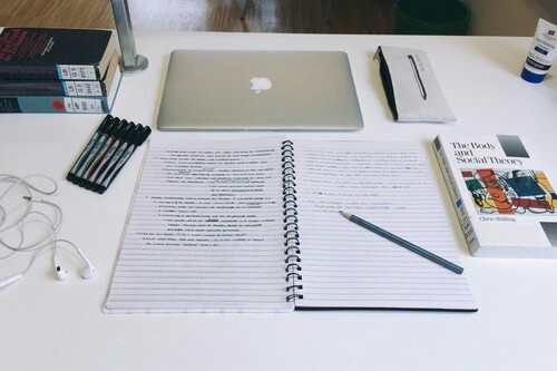 An image displaying a study layout of books, writing utensils and a laptop.