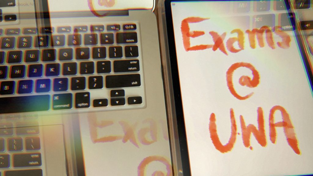 Laptop keyboard and iPad Screen reading "Exams @ UWA"