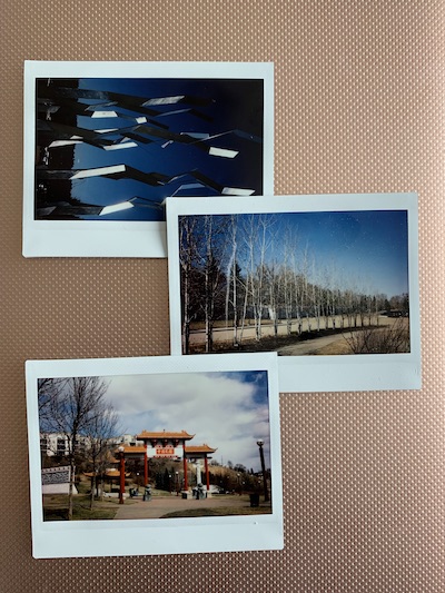 three instax photos, one of a large red building, a row of trees and a futuristic scultpure