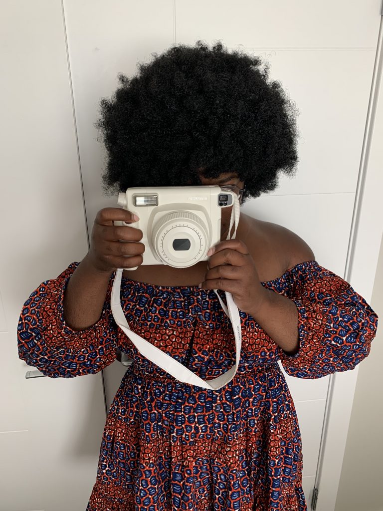 girl covering her face with a white instax wide 300 fujifilm camera