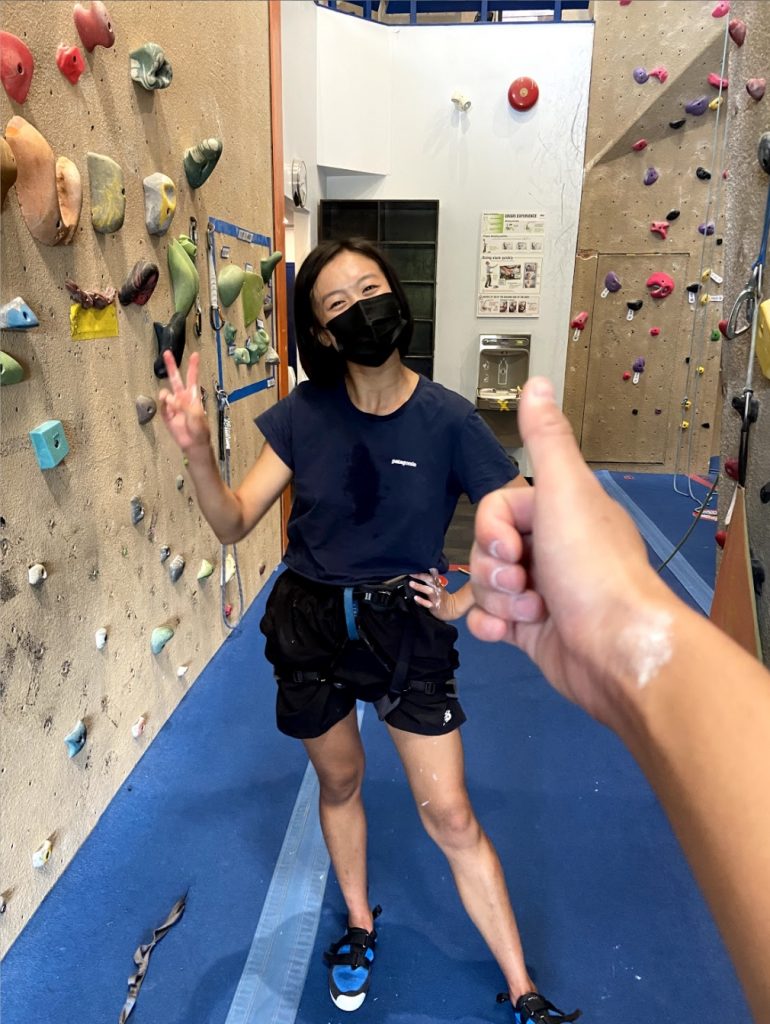 cheryl at a rock climbing gym, posing between two indoor rock climbing walls