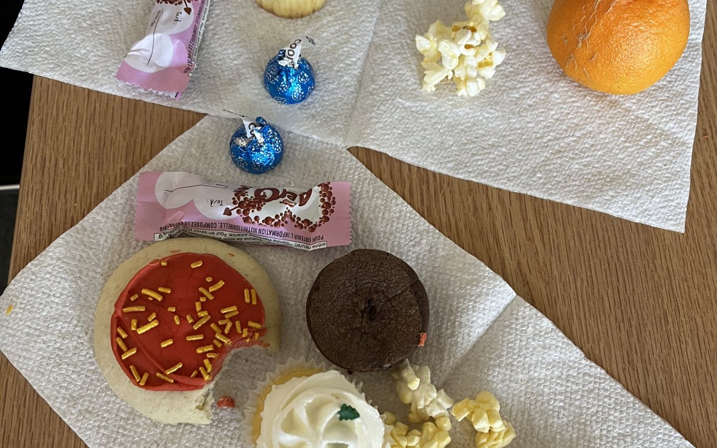 Chocolate, brownie, popcorn, cookie and an orange on a paper towel